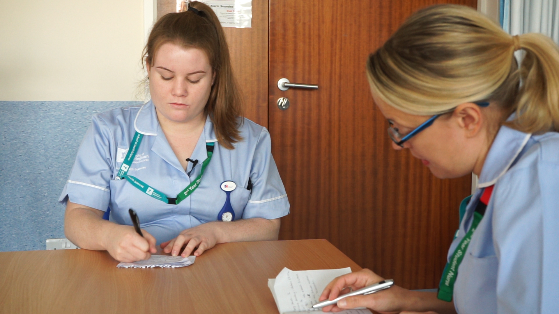 Student nurses sitting together with notepads