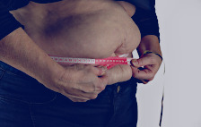 Obesity - Image of overweight person with measuring tape around their waist.