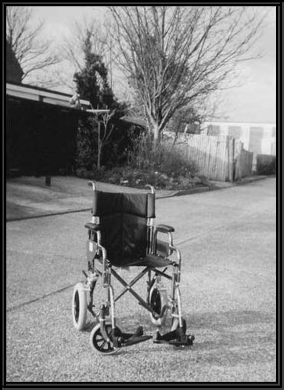 Photograph of an empty wheelchair in a hospital car park.