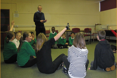 School pupils sitting in circle around teacher