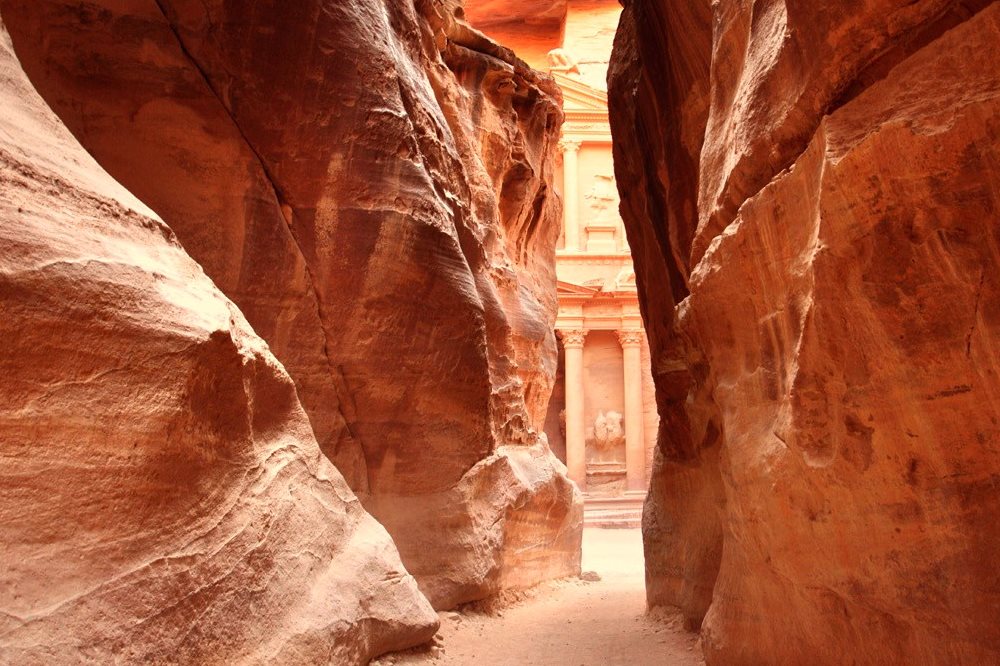 A channel through a stone mountain leads to pillars carved in the stone at Petra, Ma'an, Jordan