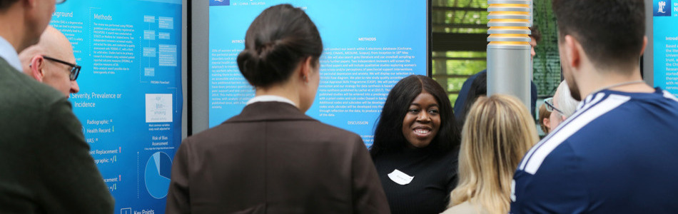 Academic Clinical Lecturer smiling at listeners in front of her research poster