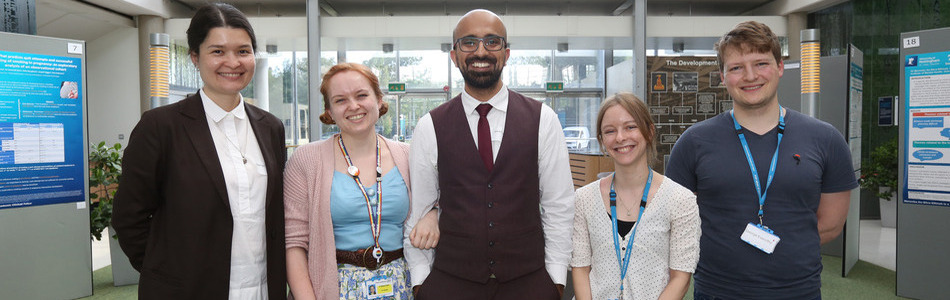 Five academics standing in a line smiling