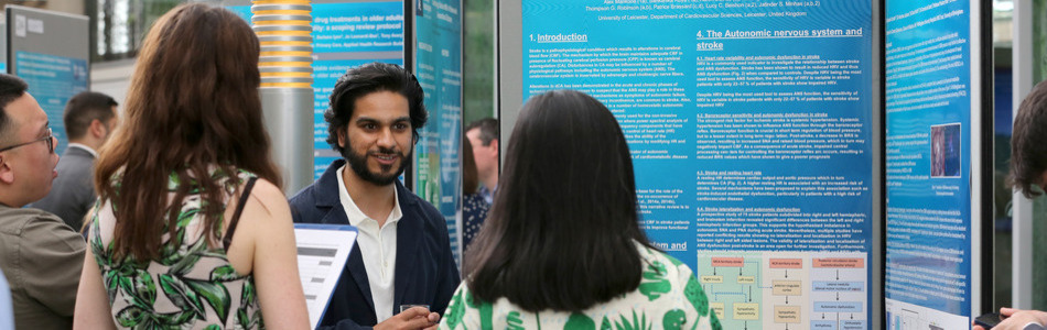 Academic talking to two women next to his research poster.