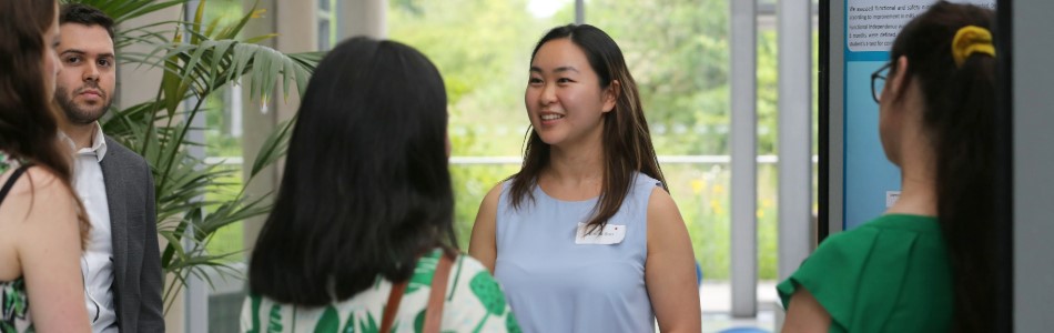 An academic smiling to observers of her research poster.