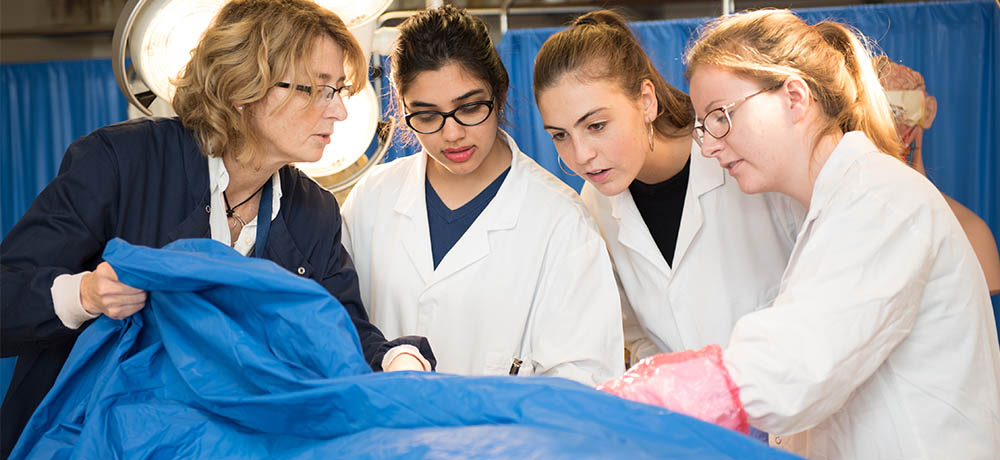 Female undergraduates and lecturer studying a cadaver