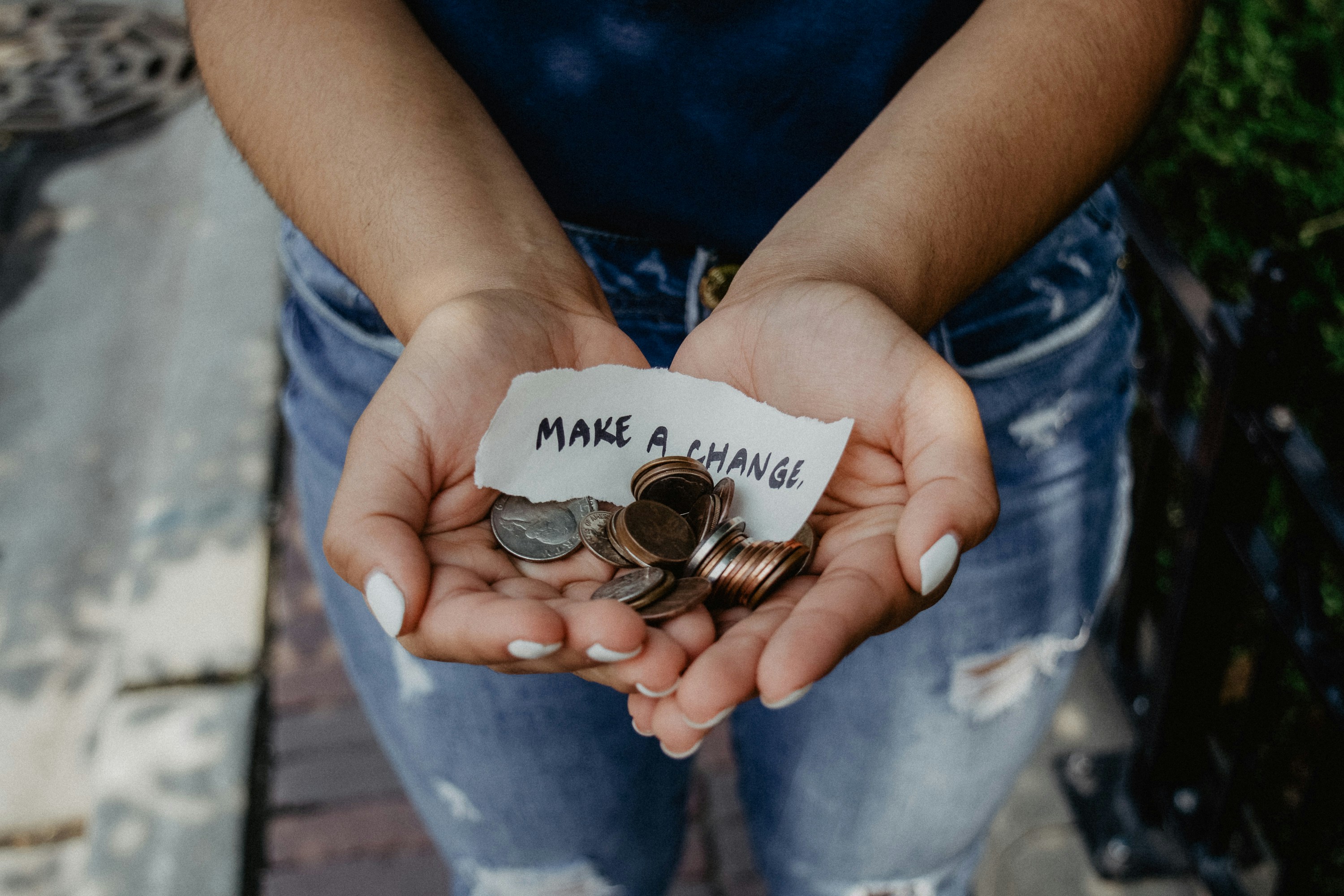 A pair of hands holding out some coins and a piece of paper that reads - make a change