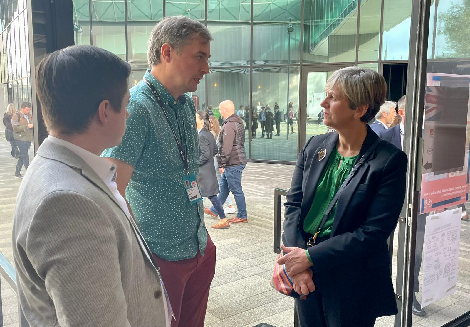 Two white men and one white lady standing and discussing