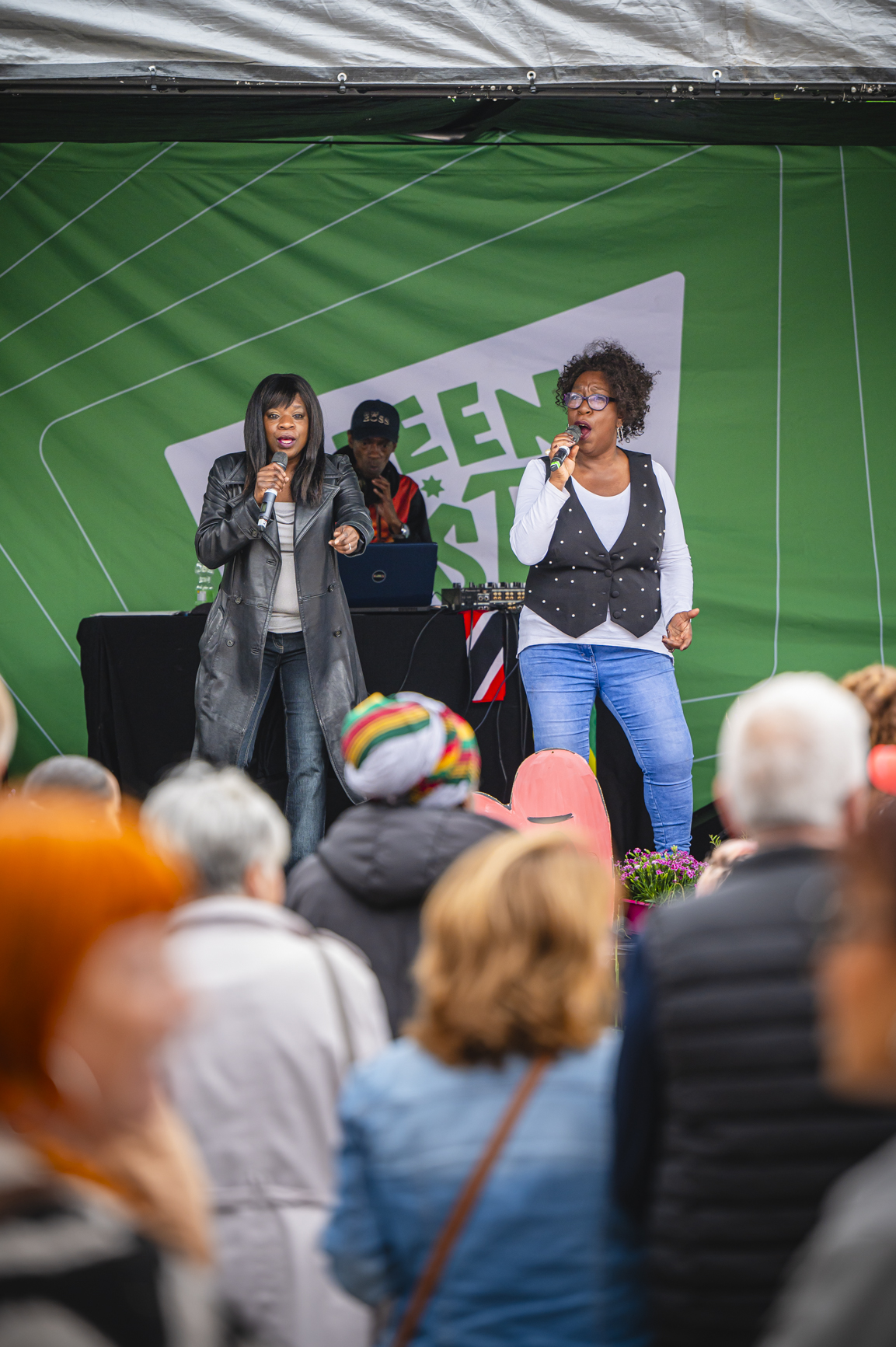 Two people on the Green Hustle stage holding mics and singing to the crowd