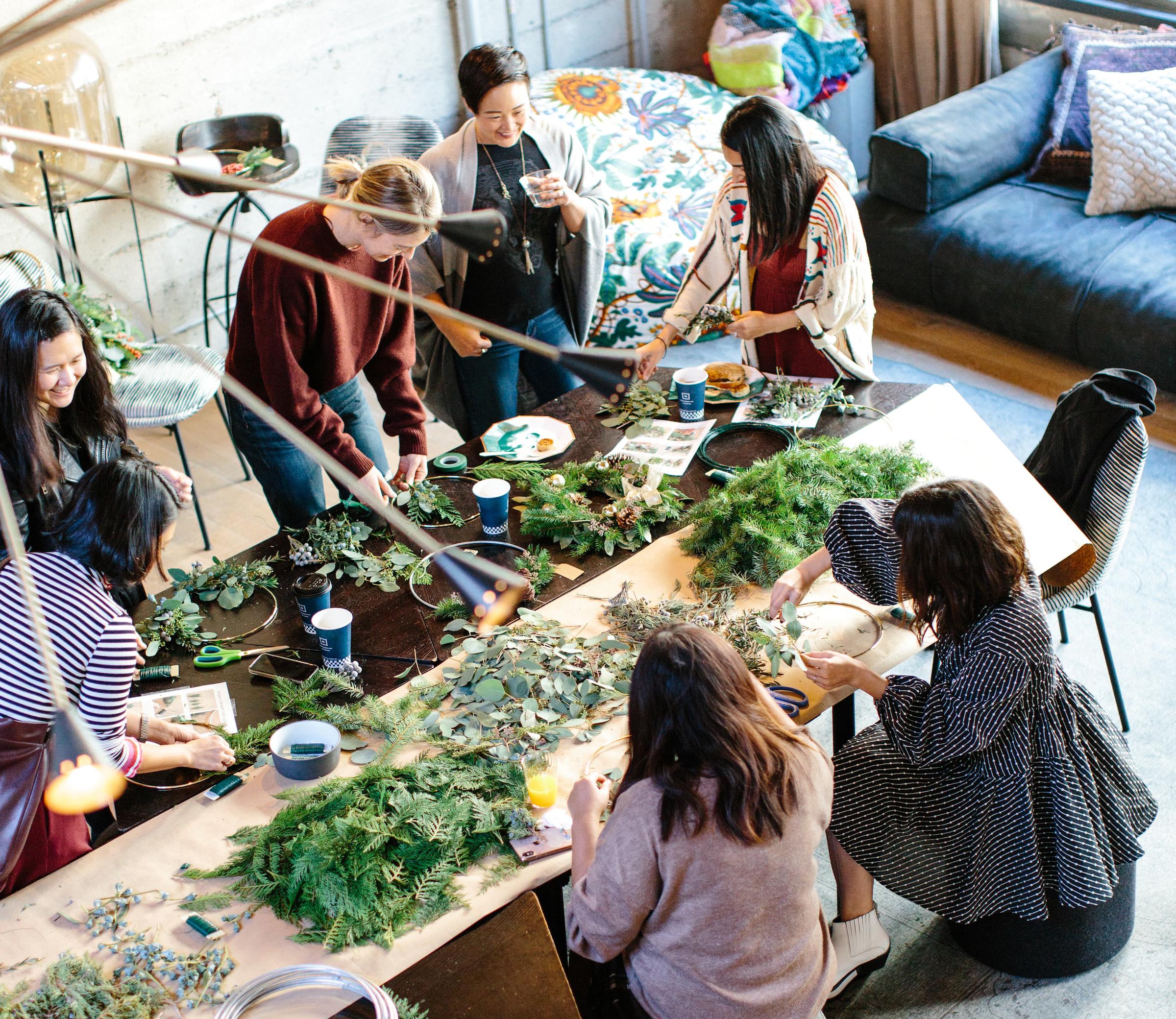 Group sat around a table in a bright workshop working with plants