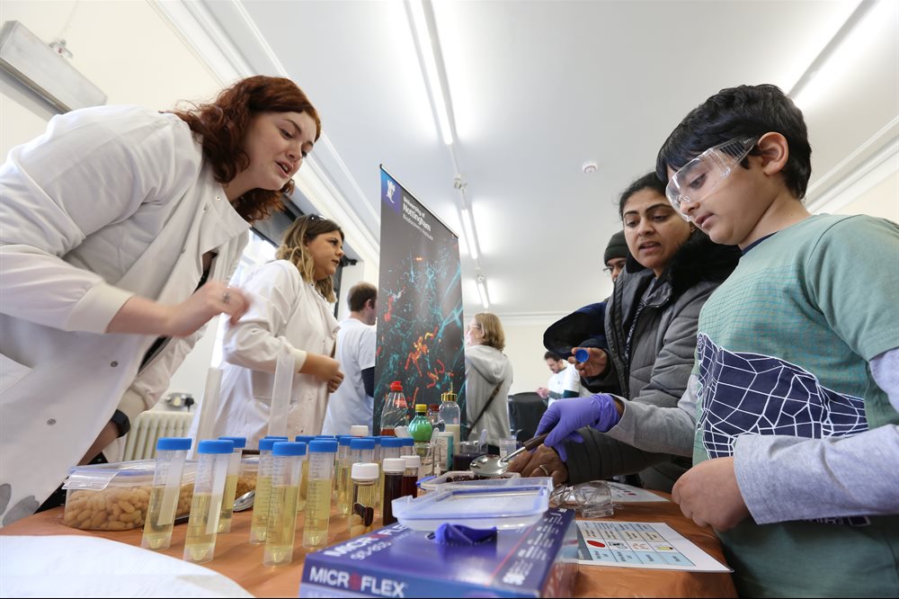 A scientist in a white coat teaching a child about an experiment.