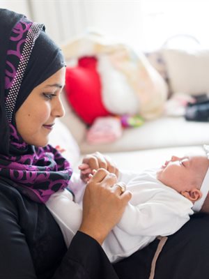 Woman wearing hijab holding baby on her lap