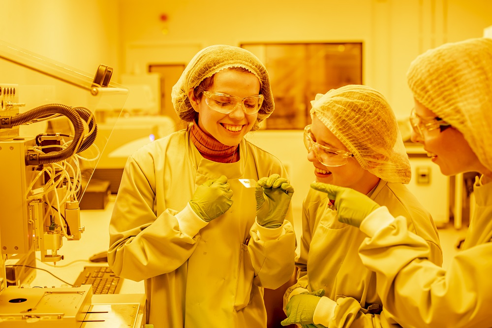STEM female researcher and students looking at a 3D printed sample in the clean room of the Centre for Additive Manufacturing at University of Nottingham
