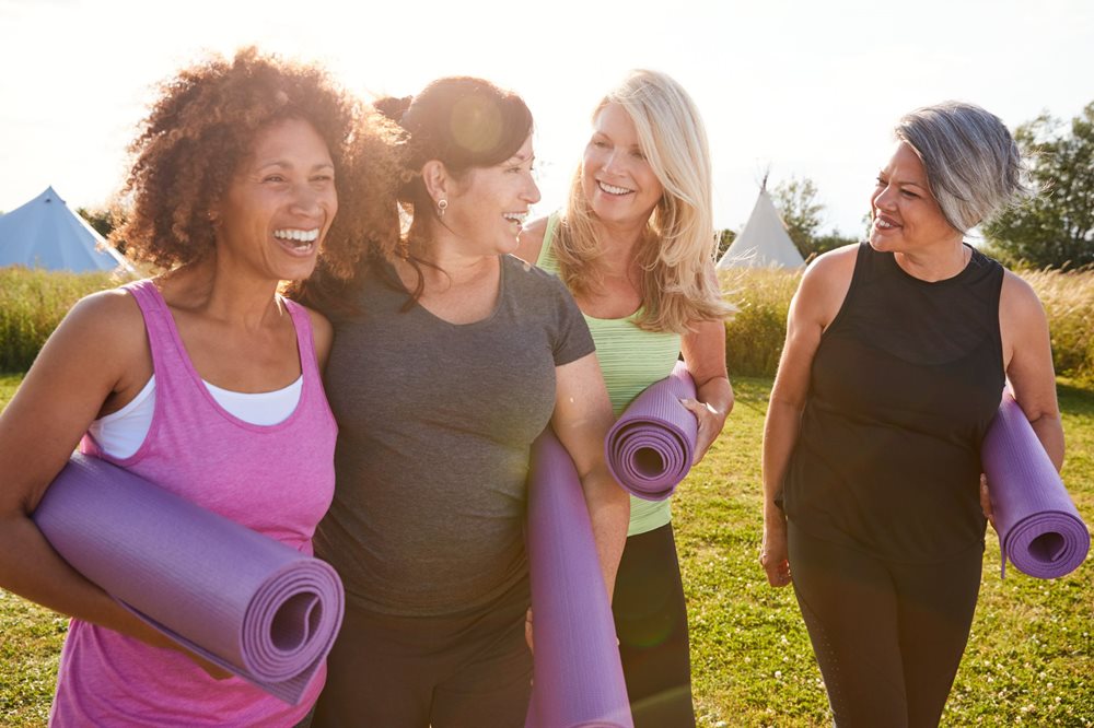 Women holding yoga mats in park