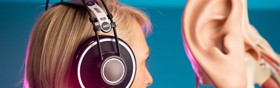 A person with headphones adjacent to a model of an ear
