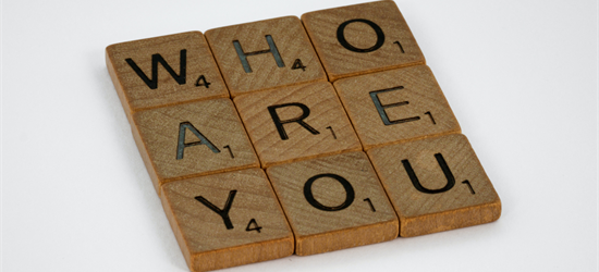 The words "Who are you" spelt out in a square of nine wooden Scrabble tiles