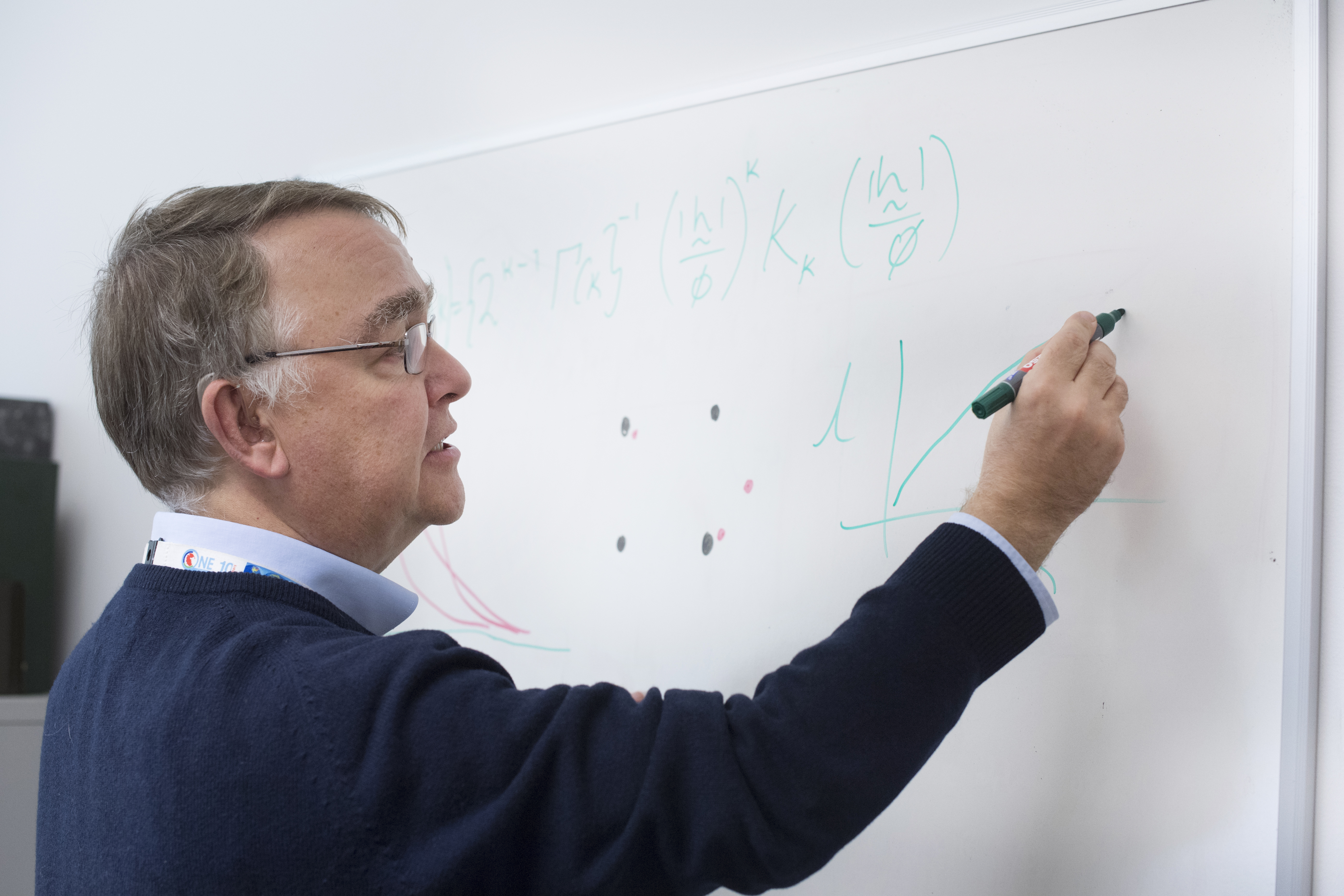 A researcher in a blue jersey writing on a white board
