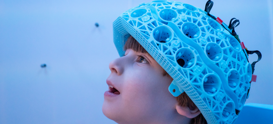Photograph of a young child wearing a new kind of wearable brain scanner.
