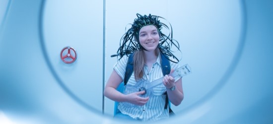 Person in brain scanner device smiling and playing guitar