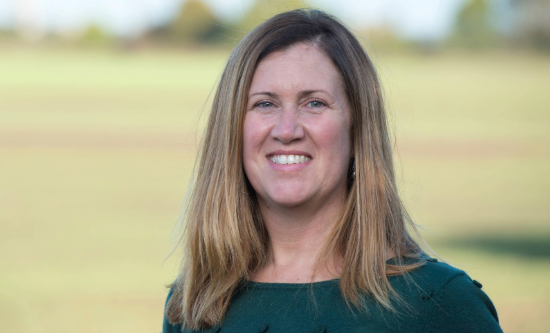 Guillermina is wearing a black blouse at a green field background