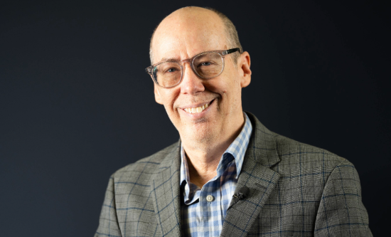 Jack Bobo wearing a brown suit and smiling in a portrait