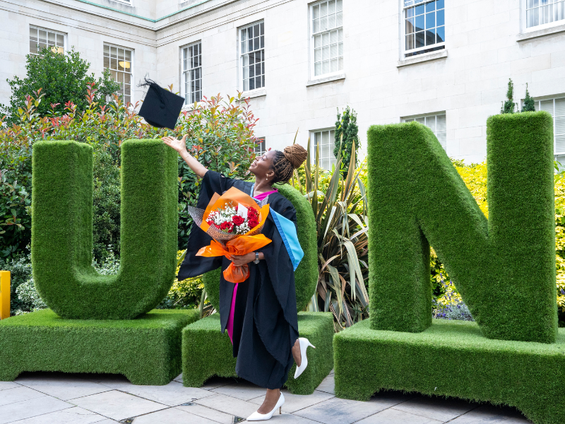 Photograph of a graduate having their photo taken in front of the giant 'UoN' letters