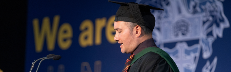 Photograph of a person making a speech at a graduation ceremony.