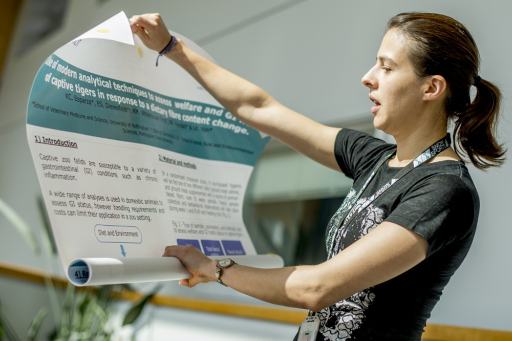 A student holding their research poster