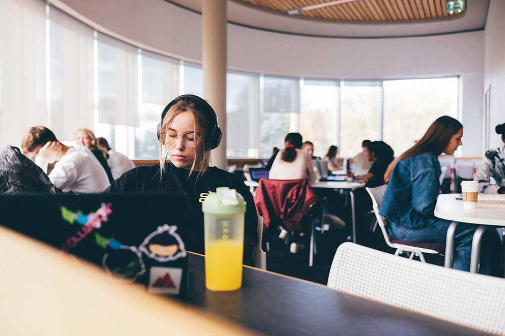 Student hearing headphones and working in a library