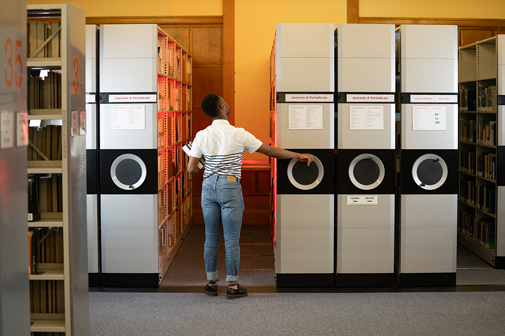 Student browsing the journal stacks with a red light