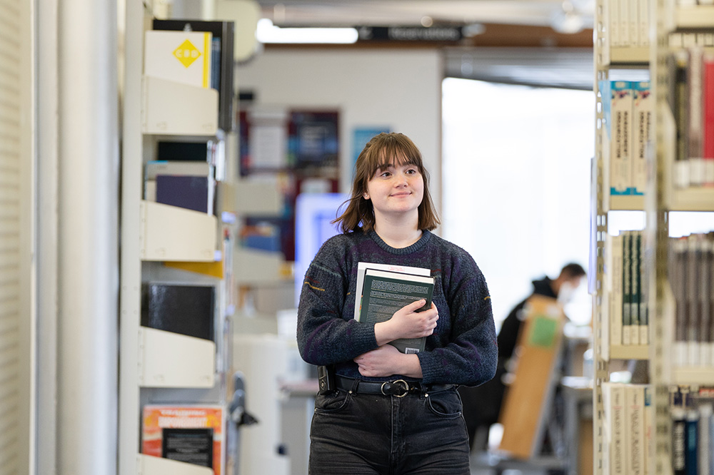 Person stood next to the stacks in a library