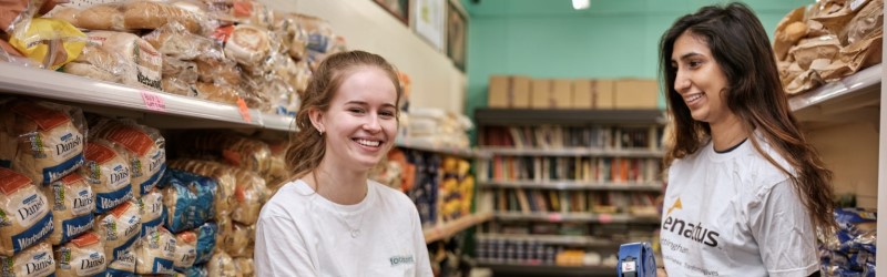 2 students wearing Enactus t-shirts in the bakery section of a shop