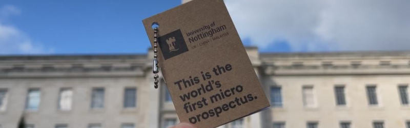 University of Nottingham microprospectus held up in the air against with a blue sky in the background