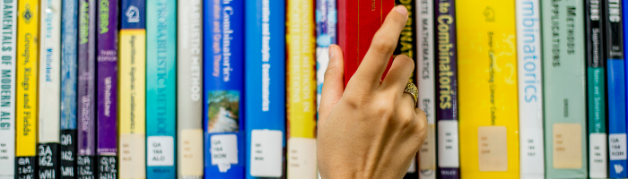 Photograph of a student's hand taking a book from a bookshelf