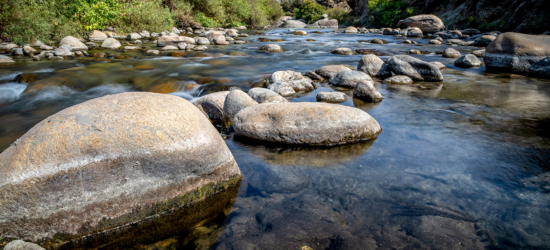 Photo of stones in the middle of a rushing river bed.