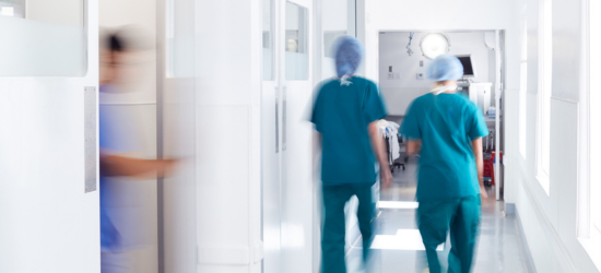 Photo of people in scrubs rushing around a hospital hallway.
